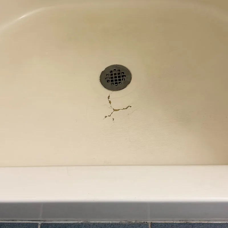 Cracked fiberglass tub floor before repair